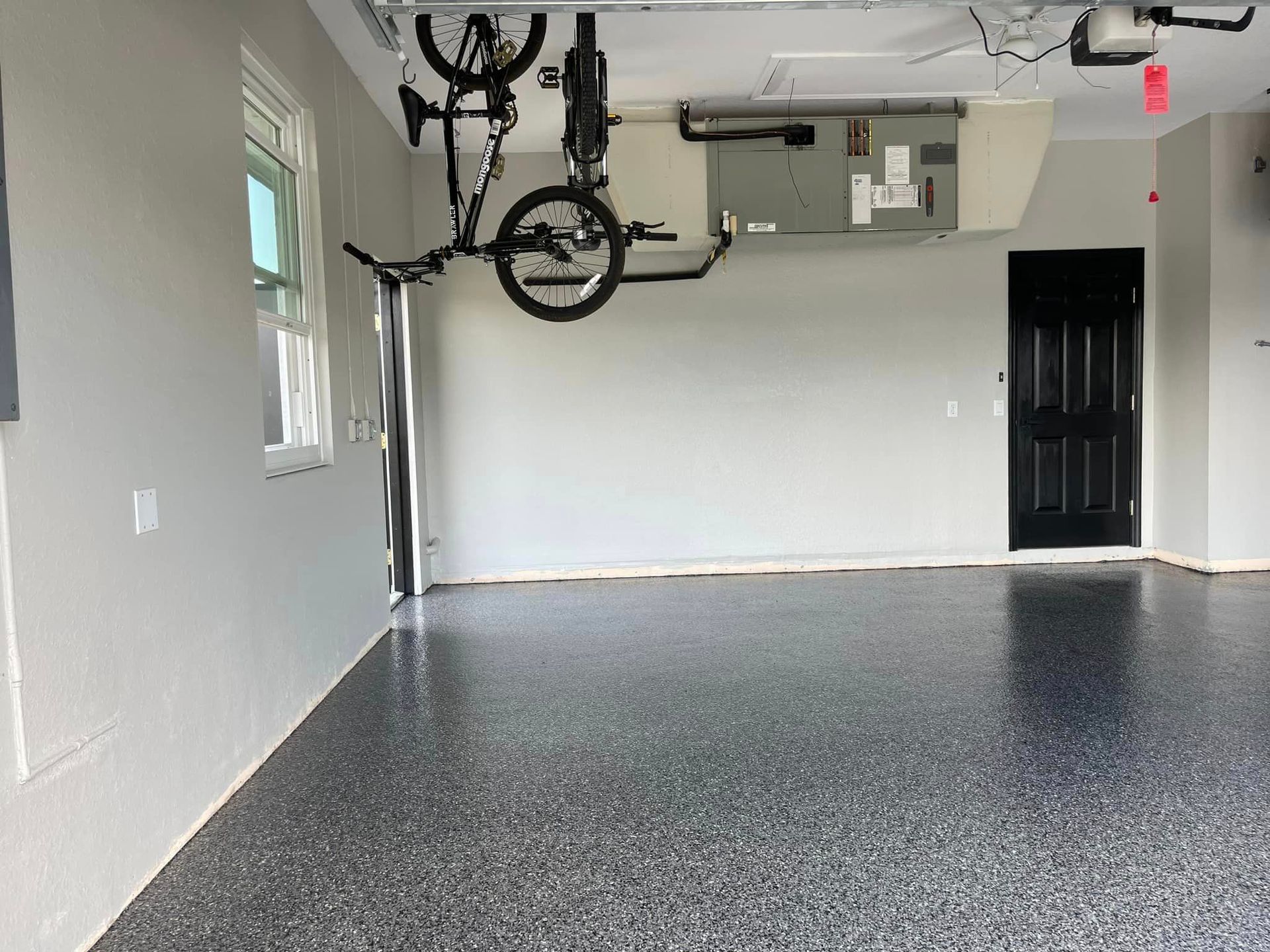 Garage with glossy, speckled floor, bike hanging, door, and white walls.