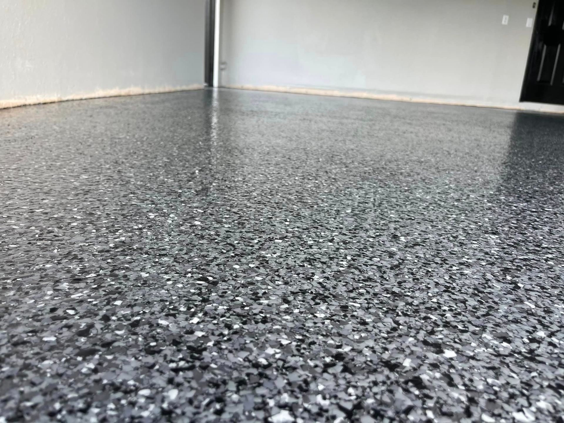 Epoxy garage floor with gray and black chips, shiny surface, light-colored walls.