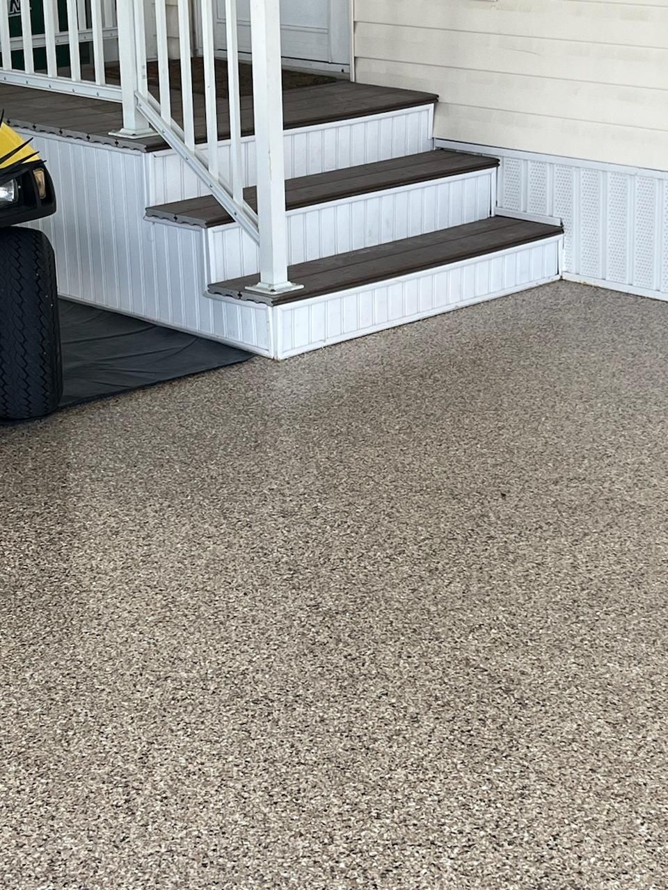 Steps leading up to a house with white railings, brown steps, and speckled flooring.