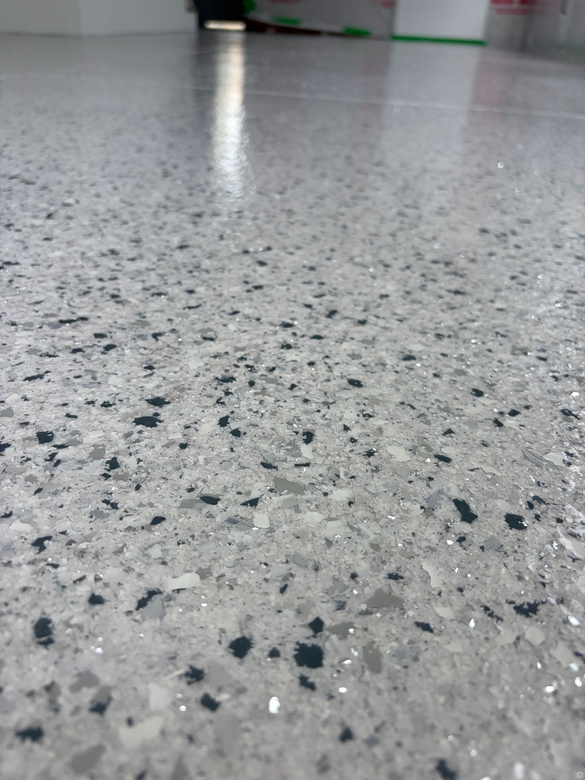 Close-up of a speckled gray terrazzo floor with a blurred indoor background.