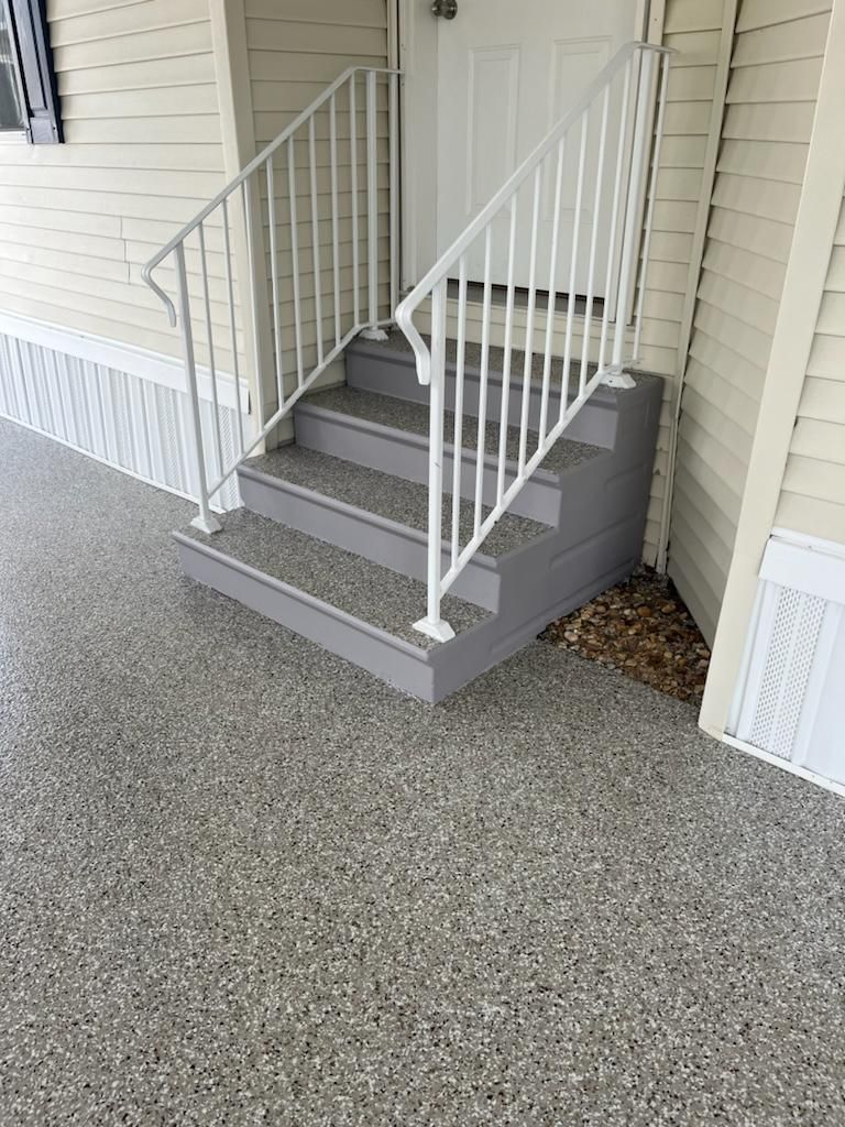 Gray steps with white railing leading to a white door; speckled gray concrete flooring.