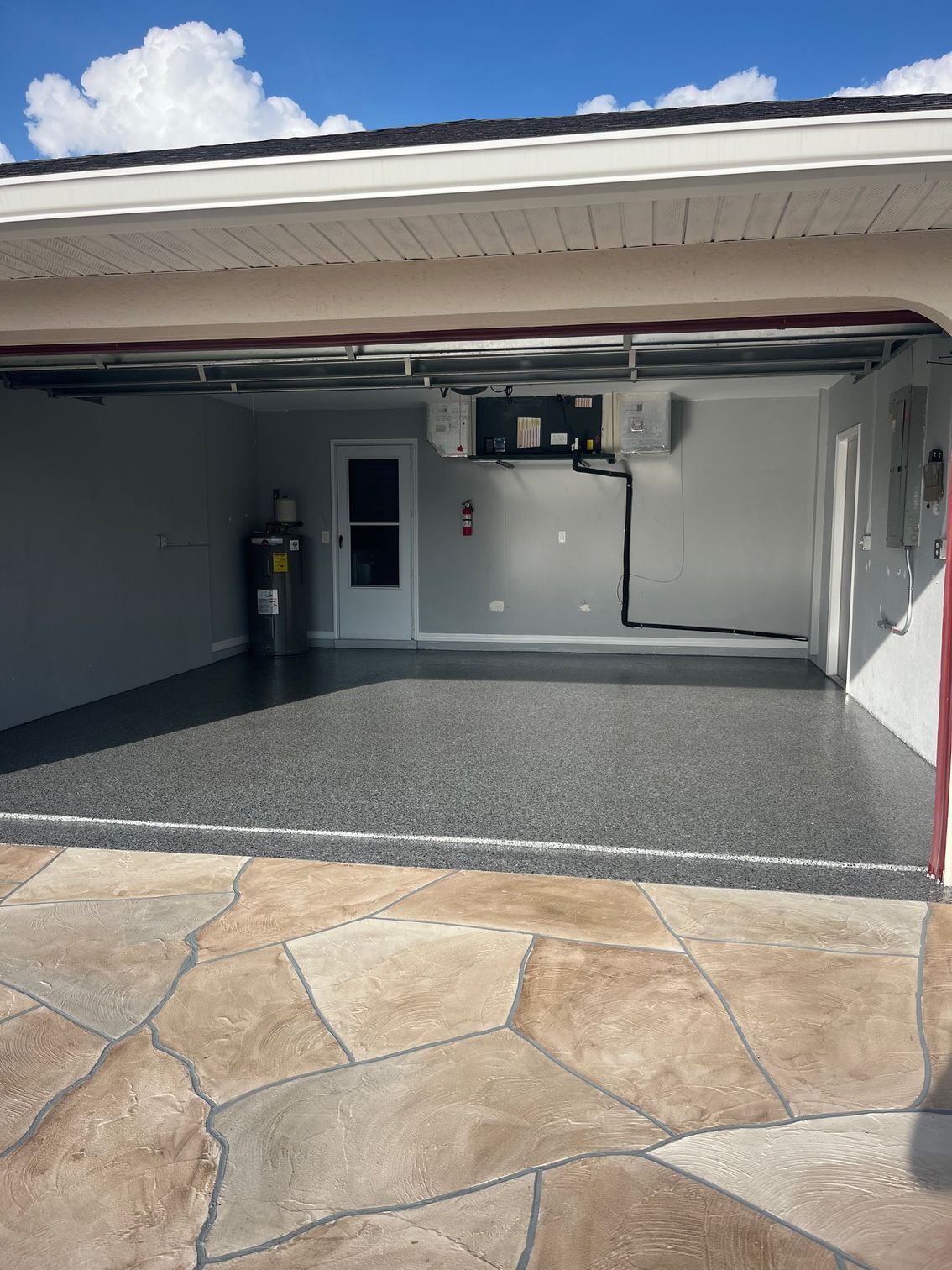 Open garage with dark gray epoxy floor, white walls, and a door.
