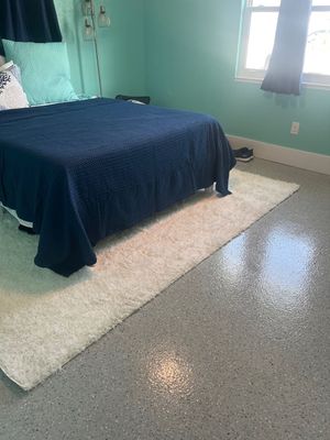 Indoor room with speckled, polished floor, framed by large windows overlooking a grassy area.