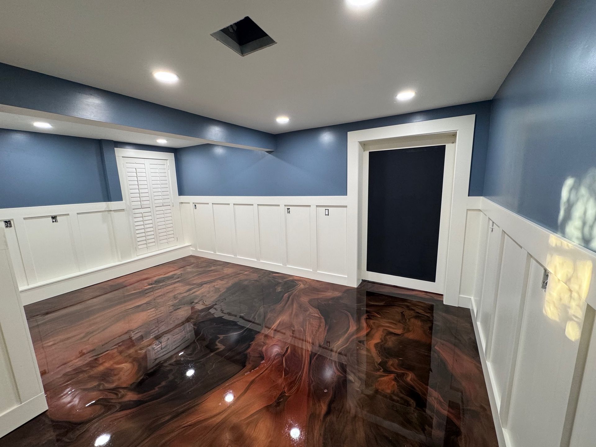 Basement with blue walls, white trim, and a metallic epoxy floor.