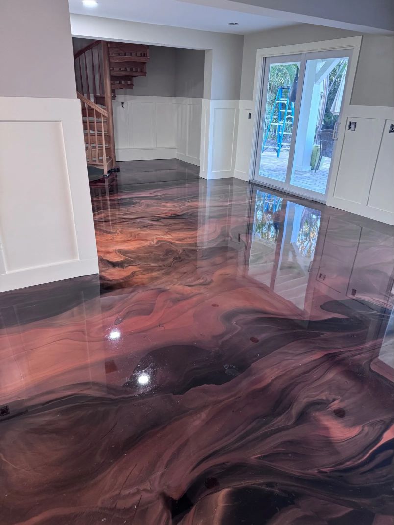 Metallic epoxy floor in tones of red, black and copper. A living space with white trim and a staircase.