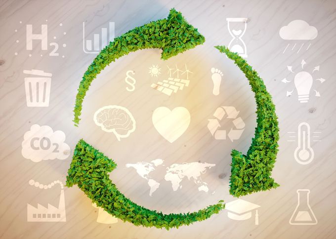 Un simbolo verde di riciclo composto da foglie, circondato da icone che rappresentano la sostenibilità, l'energia e i temi ambientali.
