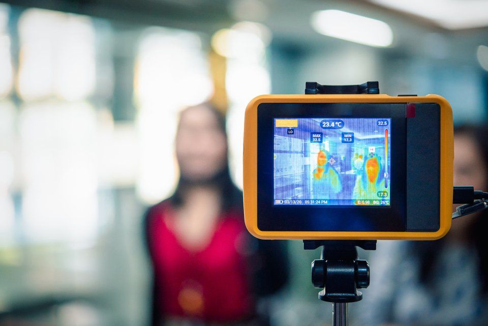 Termocamera su treppiede che riprende una persona con una maglietta rossa in un ambiente chiuso.