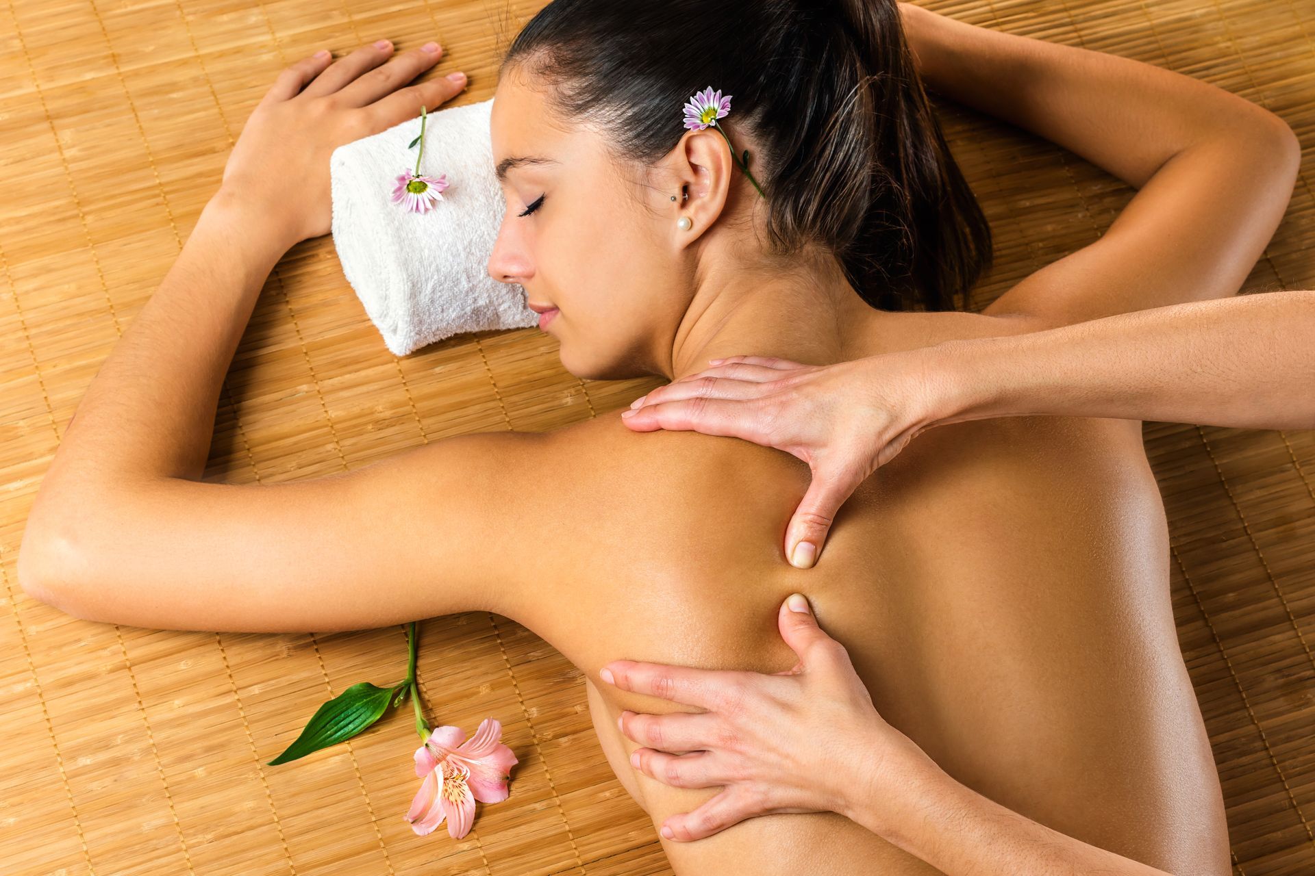 A woman lies face down receiving a back massage on a wooden surface - Thames, NZ - Thai Classic Massage Thames