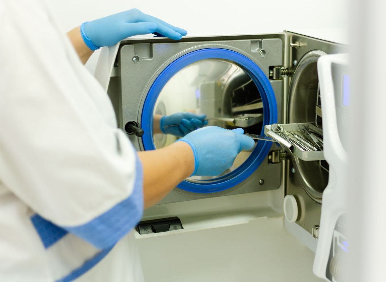 A person wearing blue gloves is working on a machine