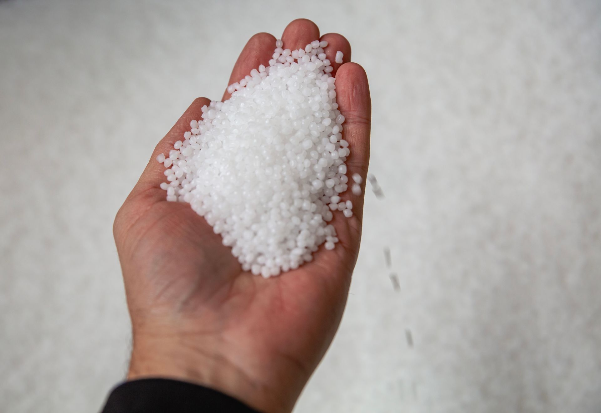 A person is holding a pile of white beads in their hand
