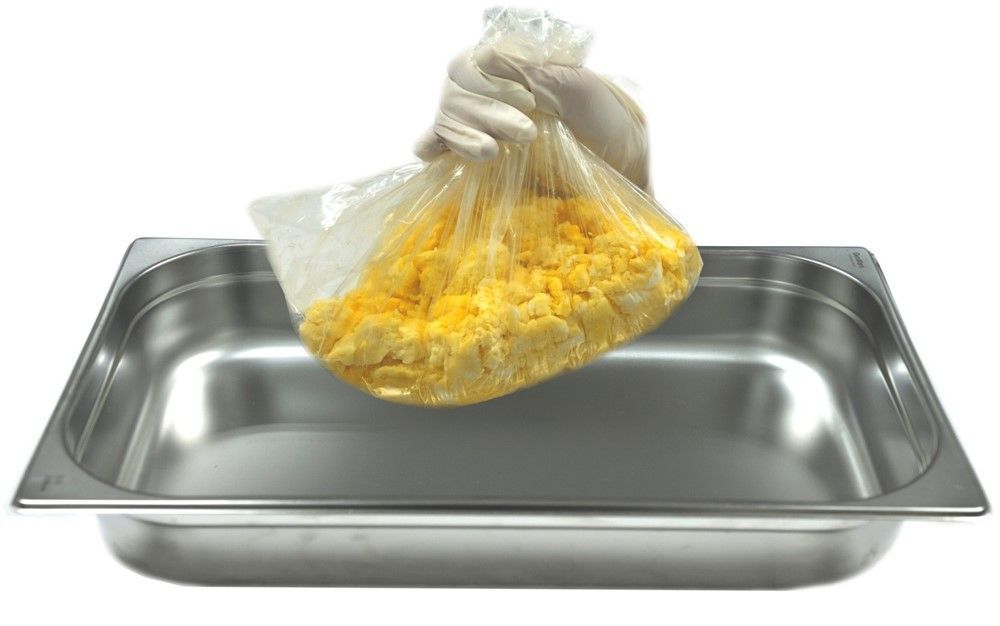 A bag of food is being poured into a stainless steel pan