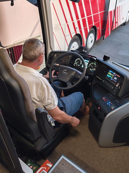 Autobus bianco con i fari accesi parcheggiato all'aperto vicino ad altri autobus al crepuscolo