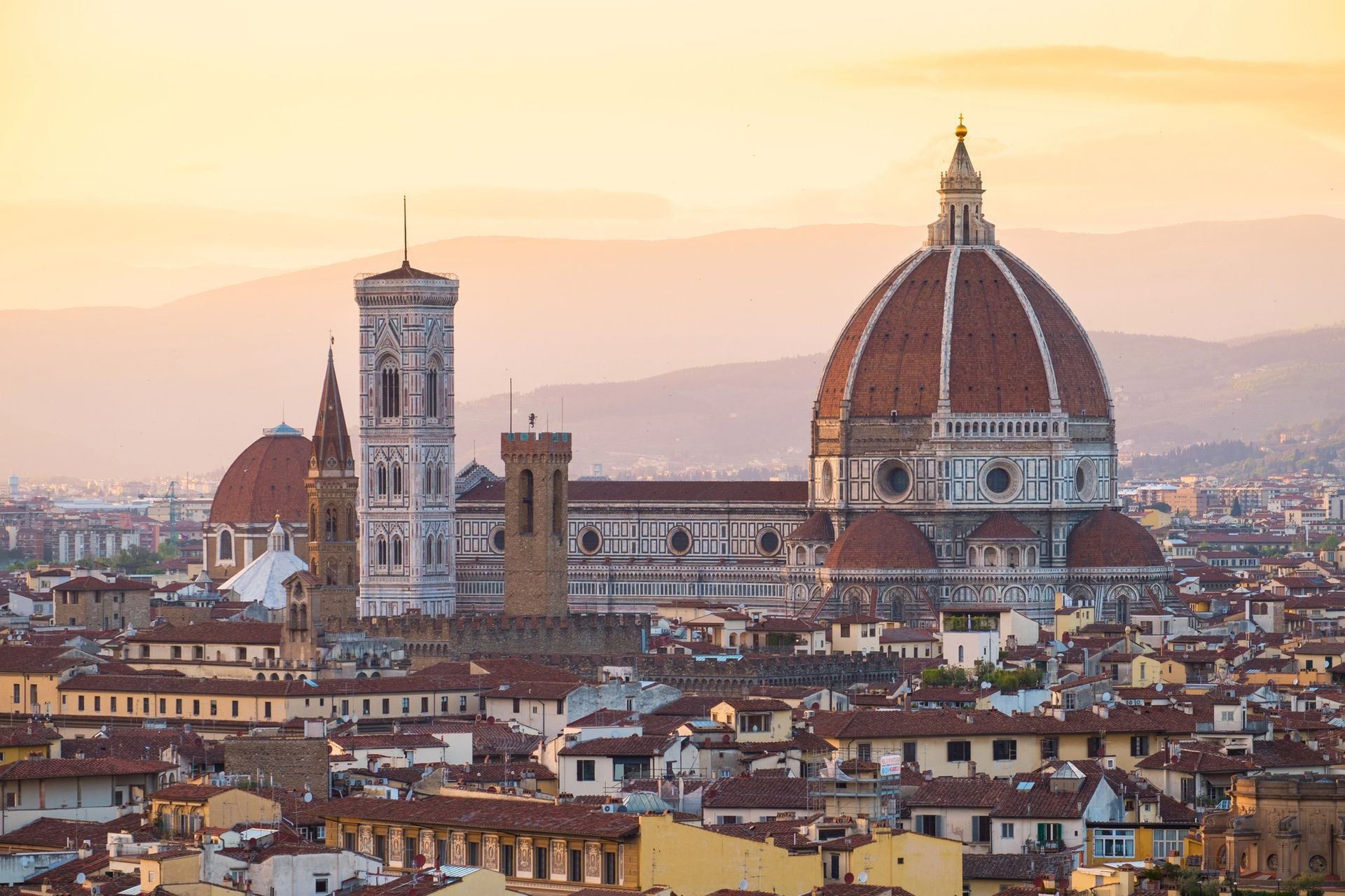 Panorama di Firenze al tramonto con il Duomo e gli edifici storici circostanti.