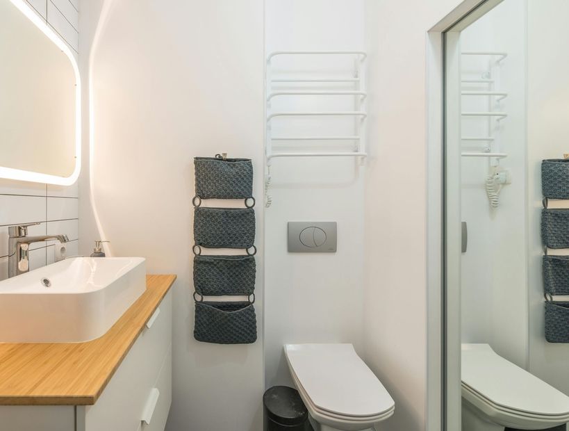 Small modern bathroom with sink, toilet, mirror, and wall towel racks