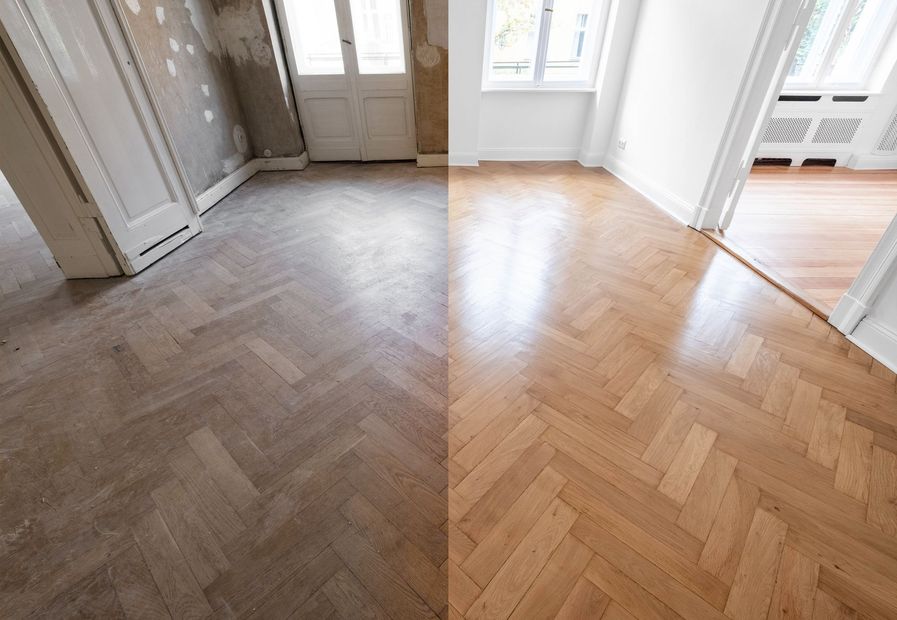 Empty room with light wood herringbone floor and white walls, lit by windows and a glass door.