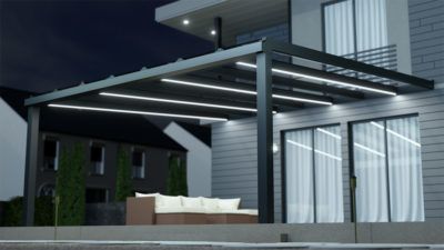 A house with a pergola and a couch underneath it at night.