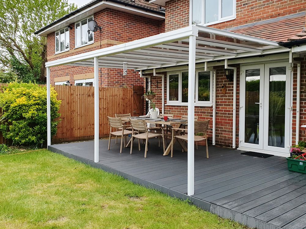 A patio with a table and chairs under a canopy in front of a brick house.