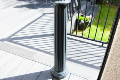 A black pole is sitting on a deck next to a railing.
