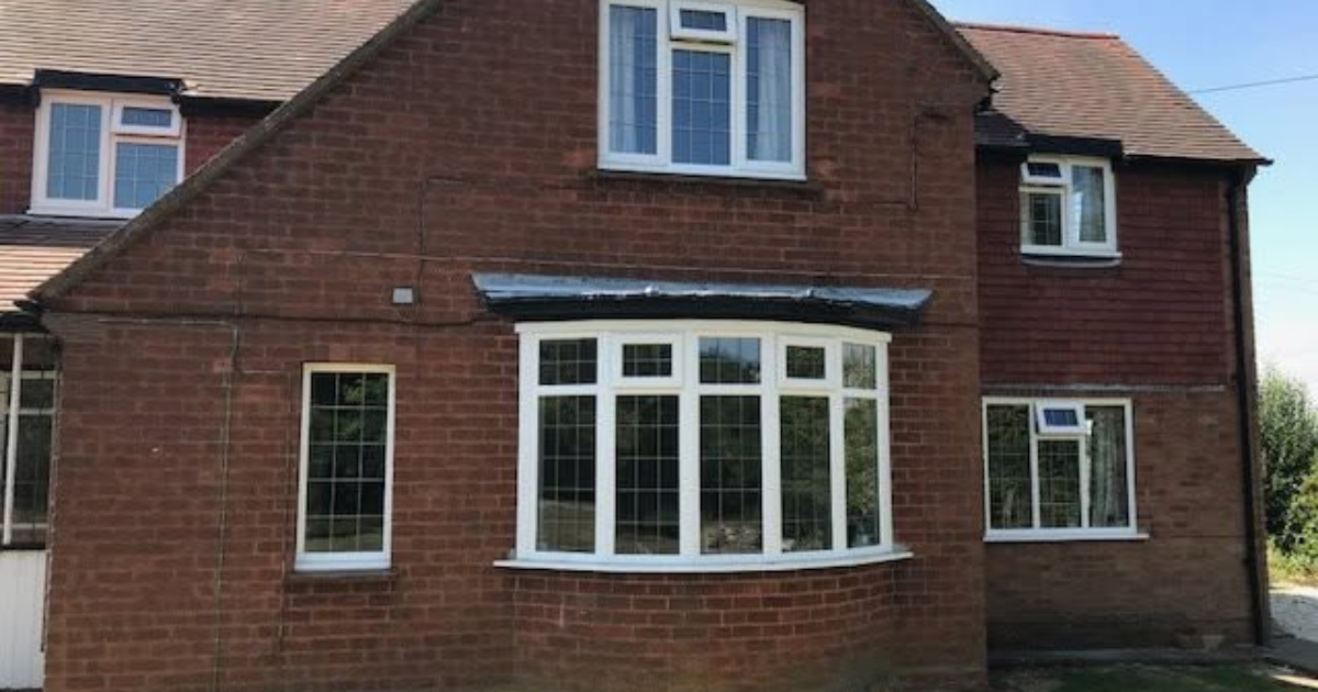 Brick house exterior with white bay windows and a red tiled roof