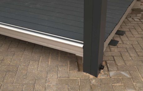 A wooden deck is sitting on a brick sidewalk next to a metal post.