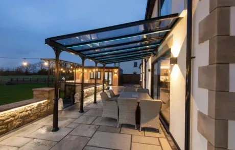A patio with a table and chairs under a glass canopy.