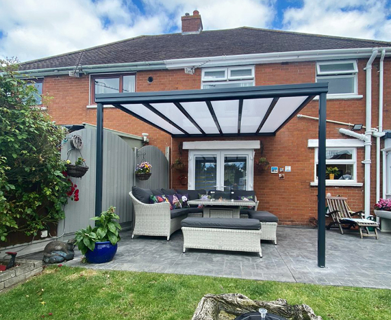 A patio with a pergola and a table and chairs in front of a brick house.