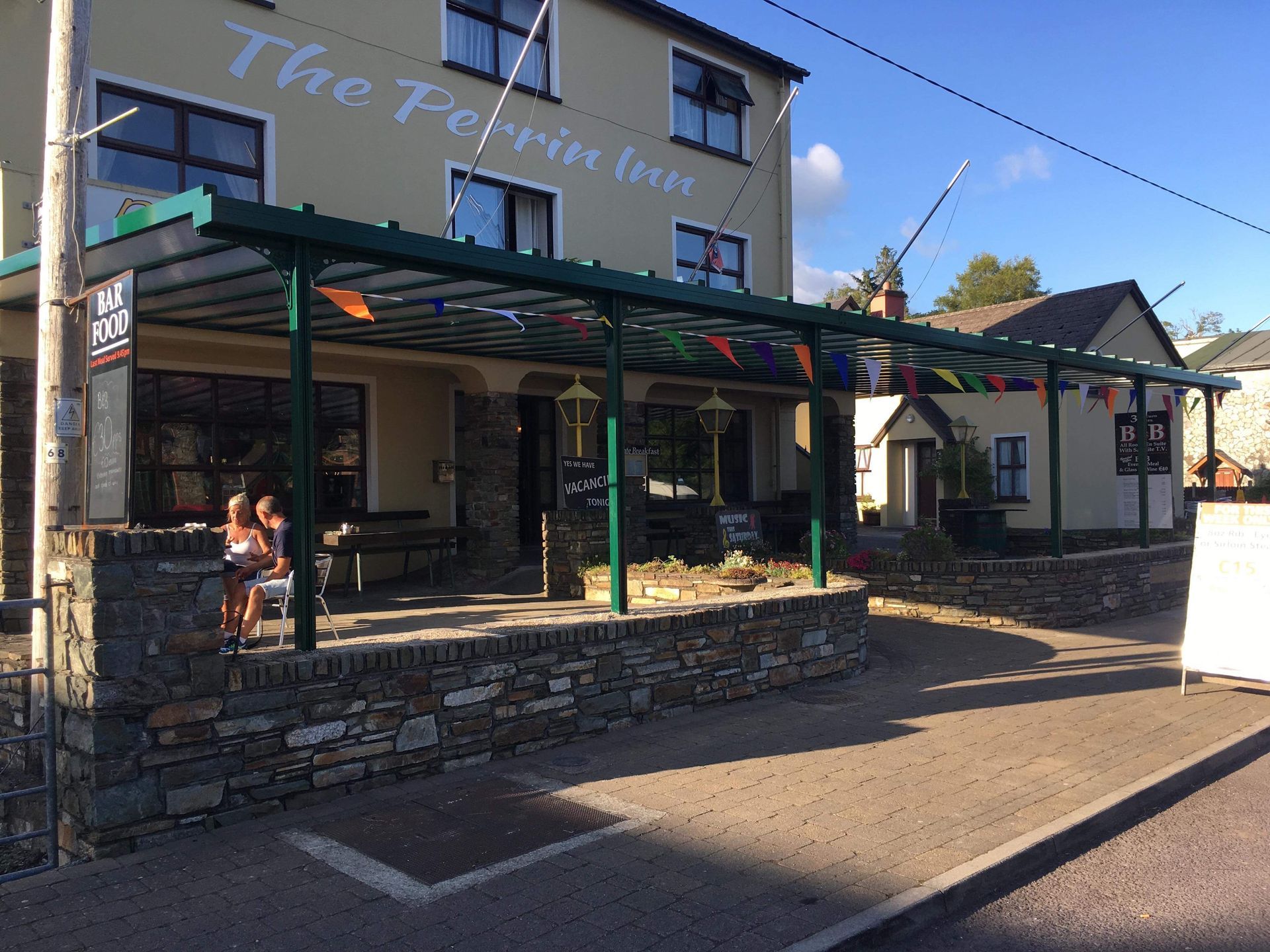 A group of people are sitting outside of a building called the perrin inn