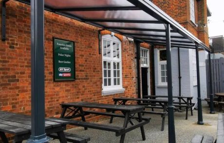 A brick building with a canopy over a patio with picnic tables.