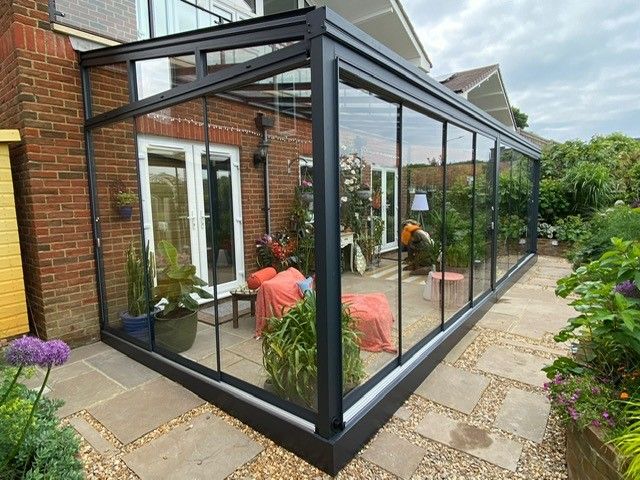 A conservatory with sliding glass doors and a brick building in the background.