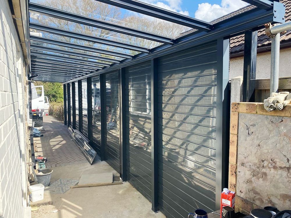 A covered walkway with a glass roof is being built on the side of a building.