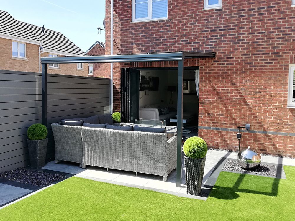 A patio with a couch and chairs in front of a brick house.