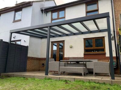 A patio with a table and chairs under a canopy in front of a house.