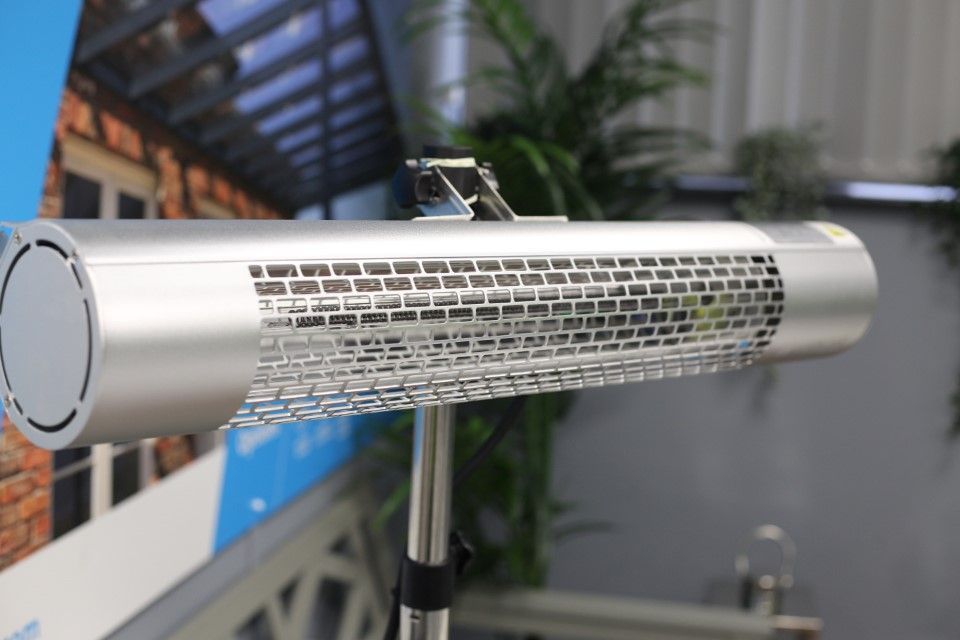 A stainless steel heater is sitting on a stand in a room.
