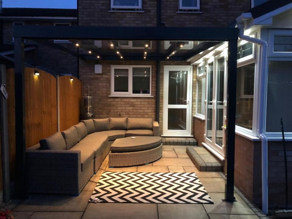 A patio with a sectional couch and a rug