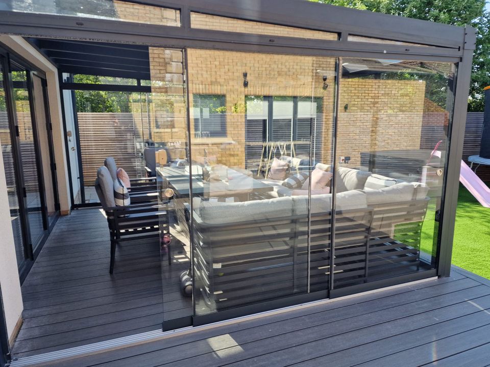A patio with a couch , chairs , table and sliding glass doors.