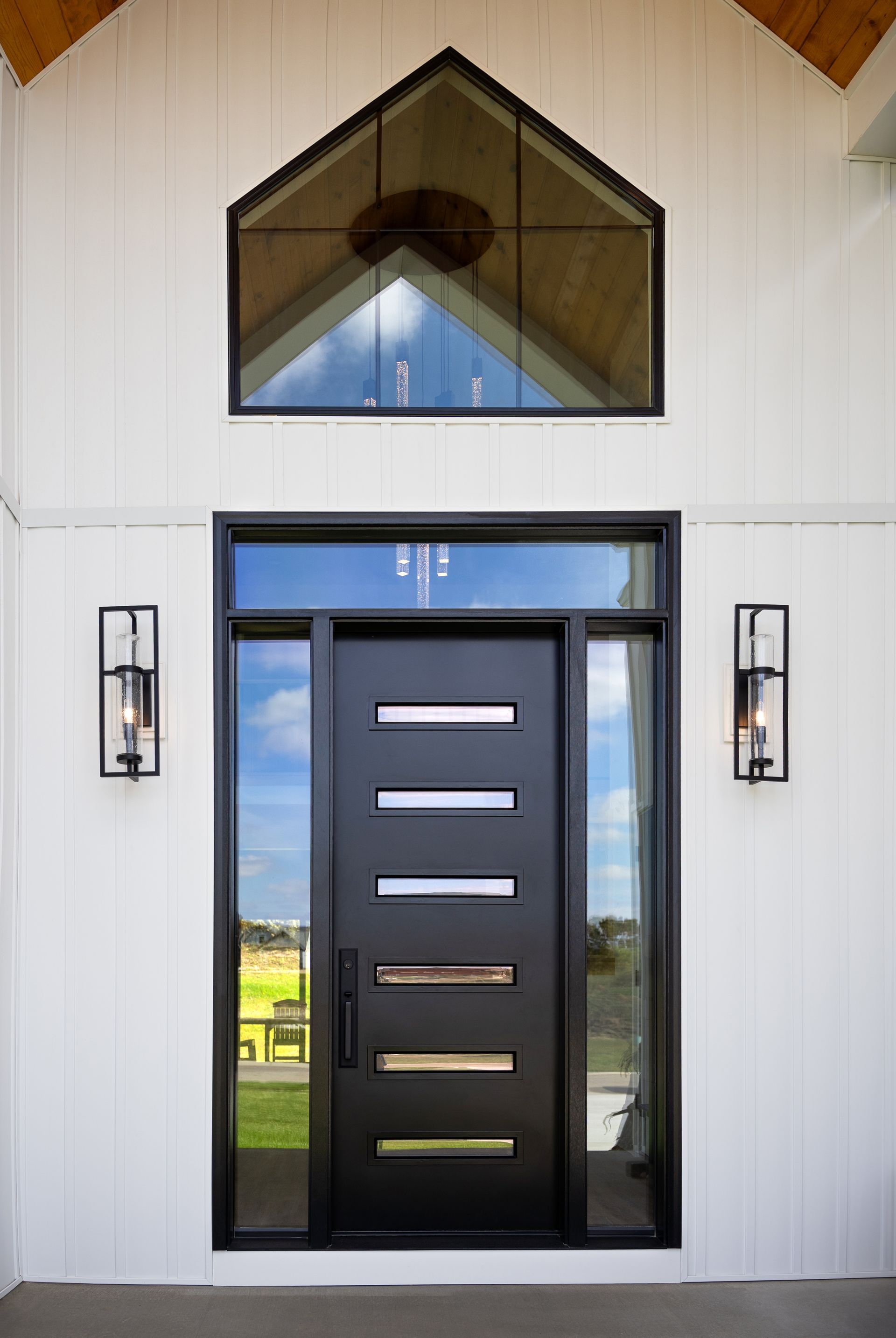 A modern front door with six horizontal windows, flanked by two side lights and topped with a transom and gable window.