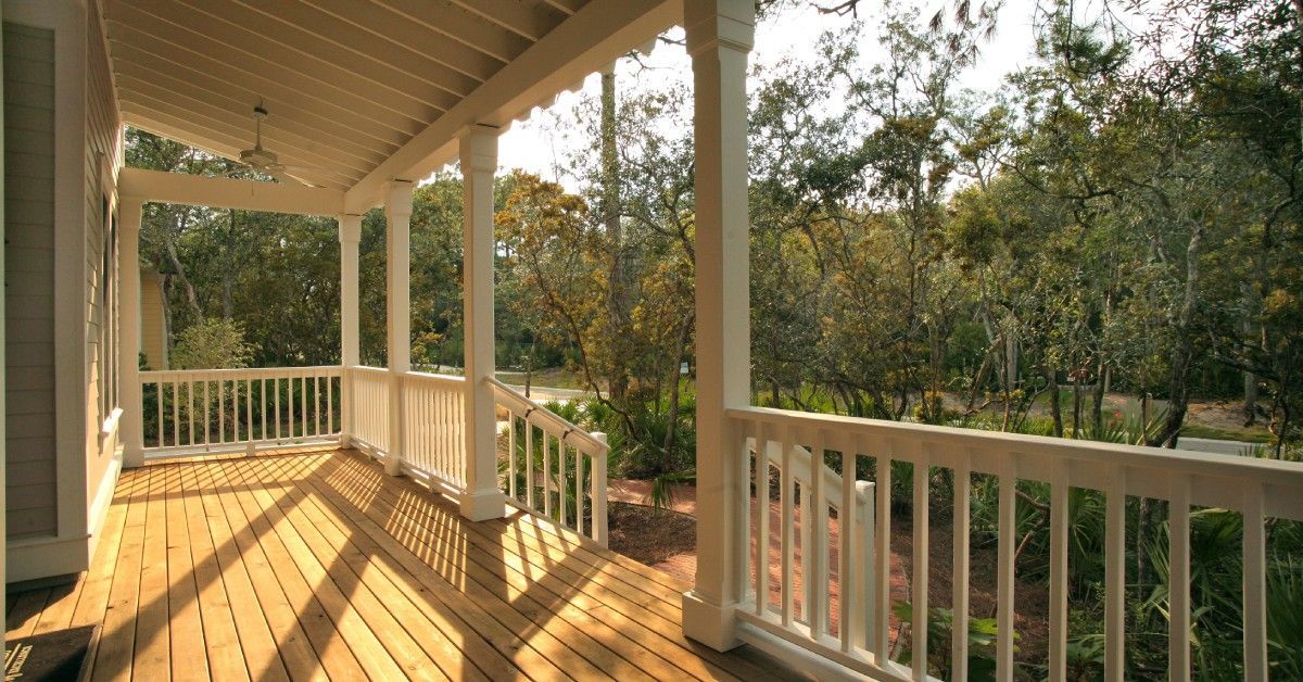 A covered porch with the sunlight streaming in and highlighting the wooden boards. It has stairs leading up to it.