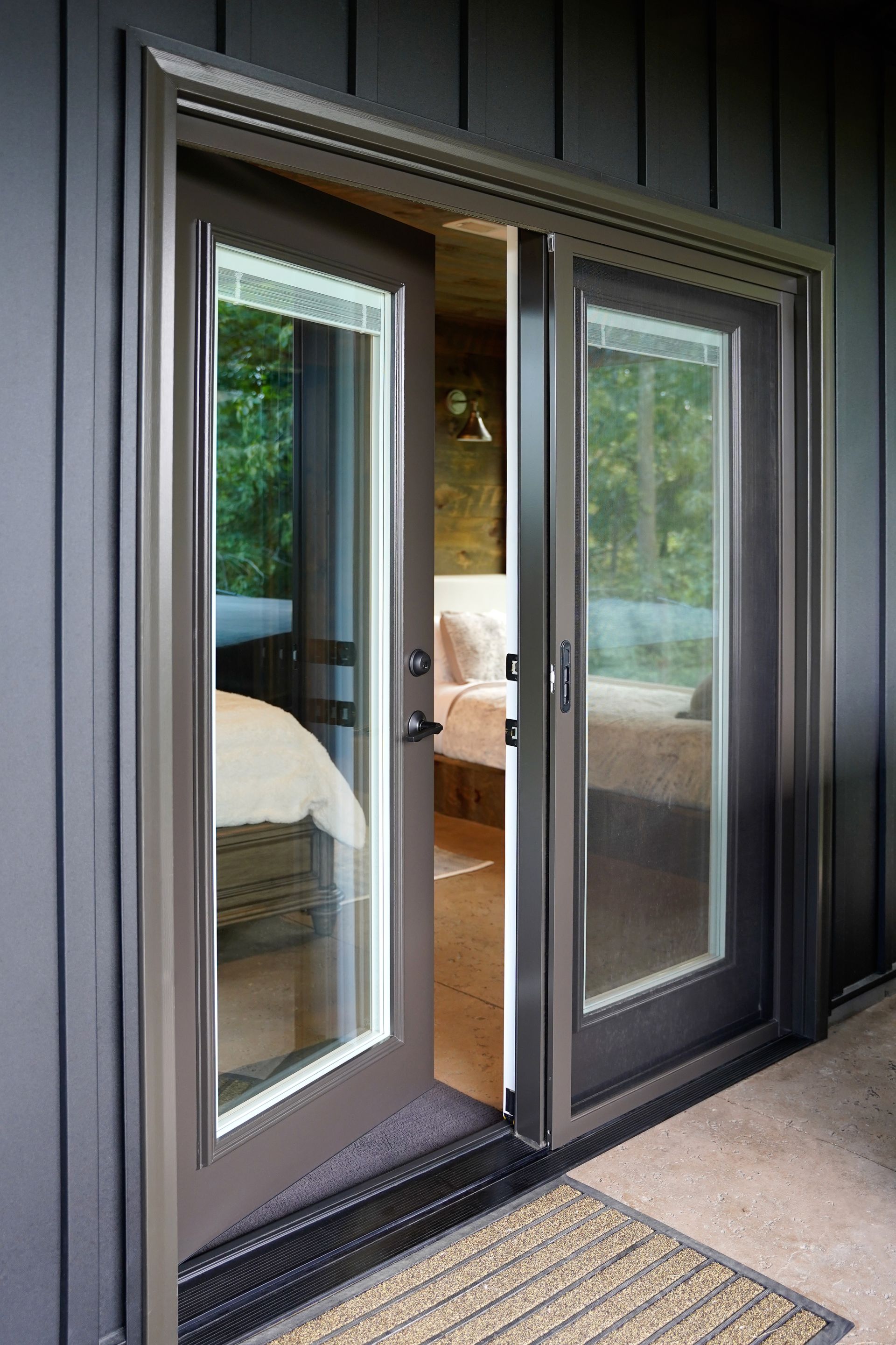 A pair of dark-framed French doors stands slightly open, revealing a glimpse of a bedroom interior against a black wall.