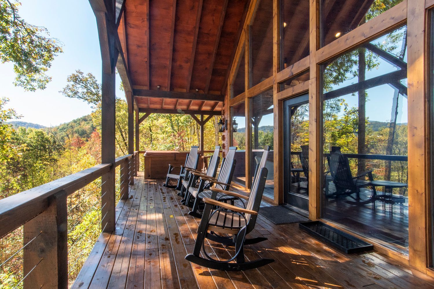 Wooden cabin porch with rocking chairs overlooking a tree-filled valley.