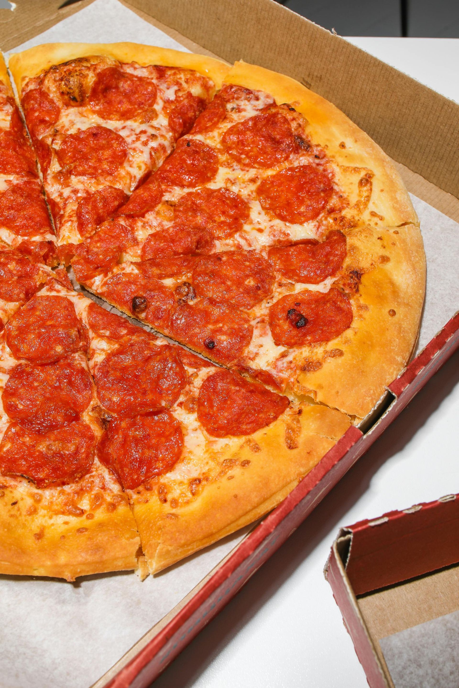 Pepperoni pizza in cardboard box. Sliced and ready to eat.