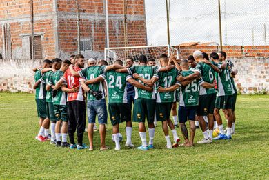 Soccer team in green jerseys huddles on a grassy field before a match