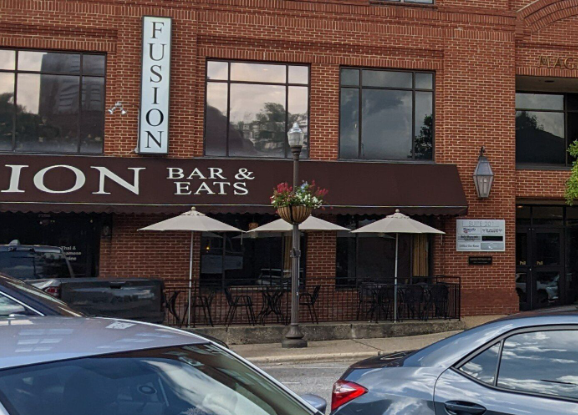 Storefront with “FUSION Bar & Eats” sign, awnings, and parked cars in front