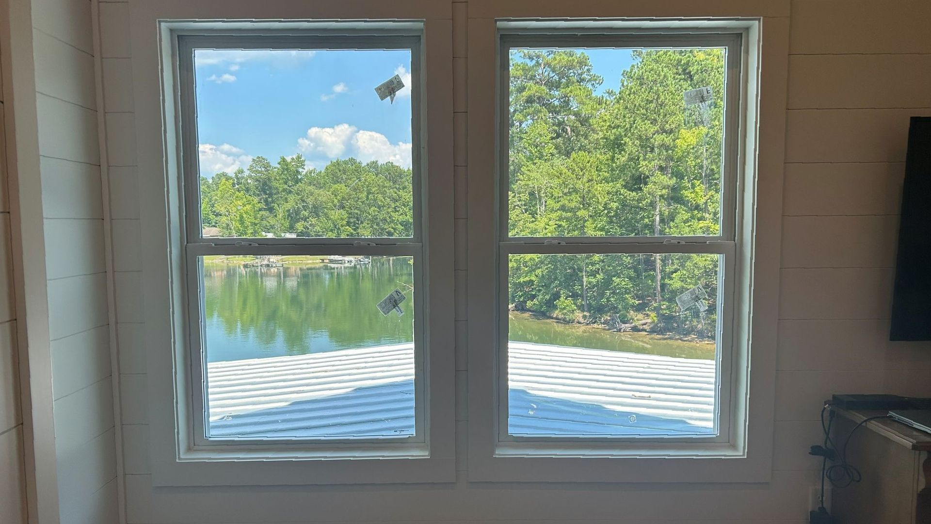 Two windows overlooking a lake and trees on a sunny day
