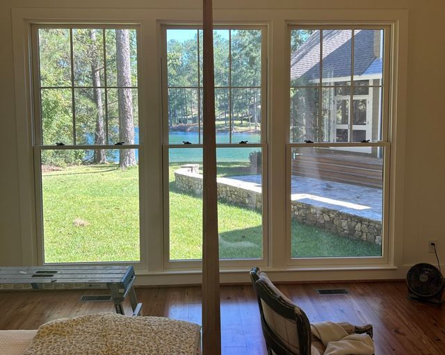 Living room view of a sunny backyard with pool and patio through large glass doors