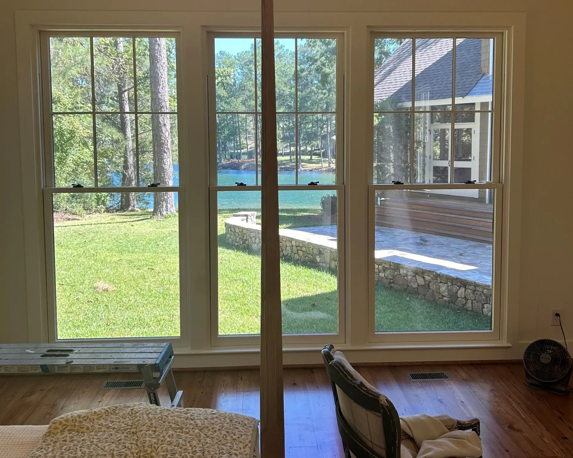 Living room view through large windows to a sunny backyard and swimming pool