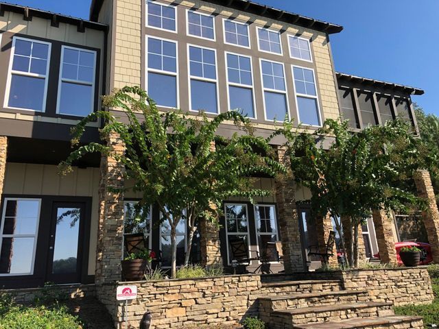 Modern multi-story building with large windows, stone facade, and vines over a front entrance.