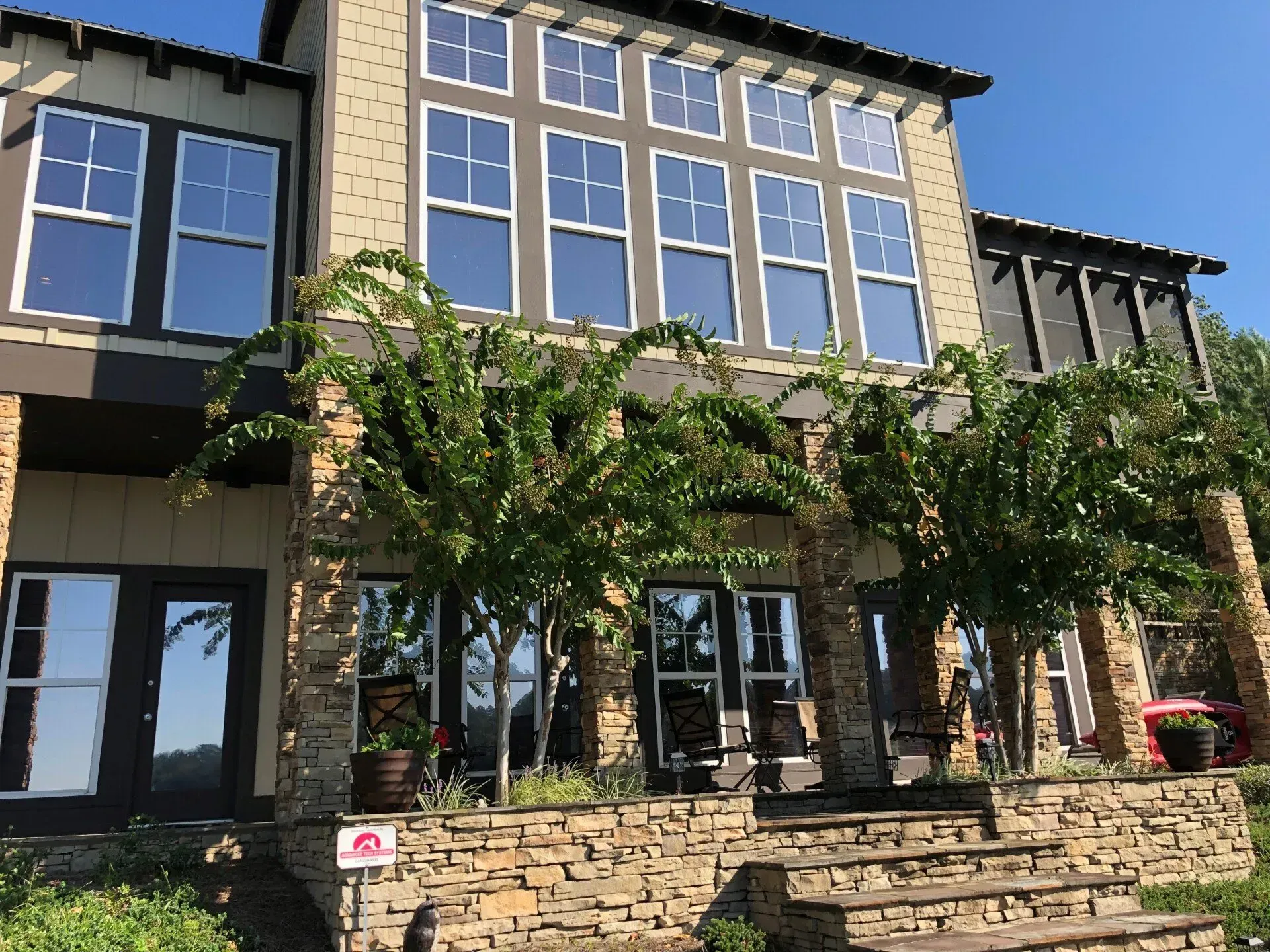Stone apartment building with large windows, balconies, and a vine-covered patio in front