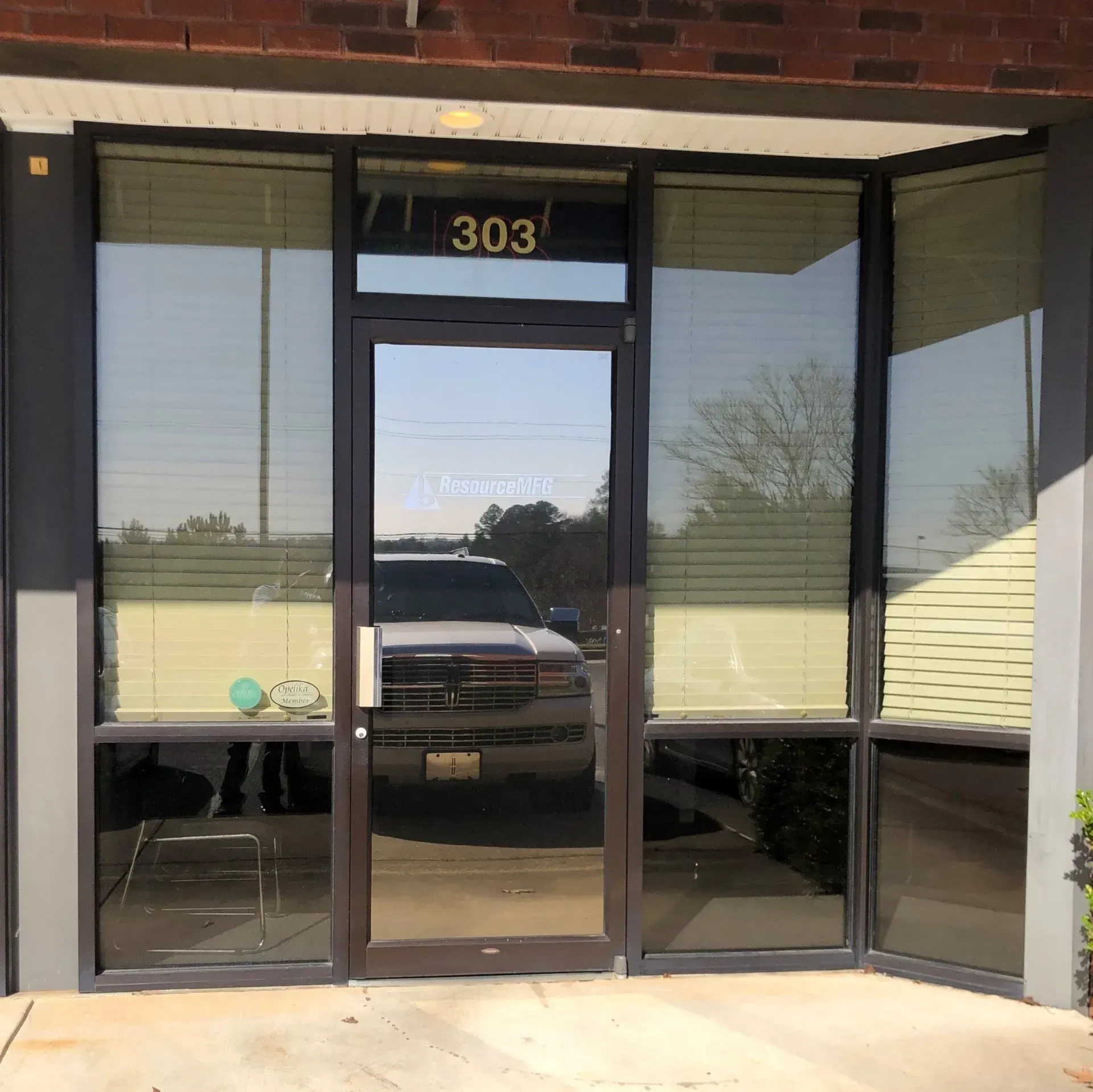 Glass storefront entrance with black-framed doors and windows, unit 303 above the door.