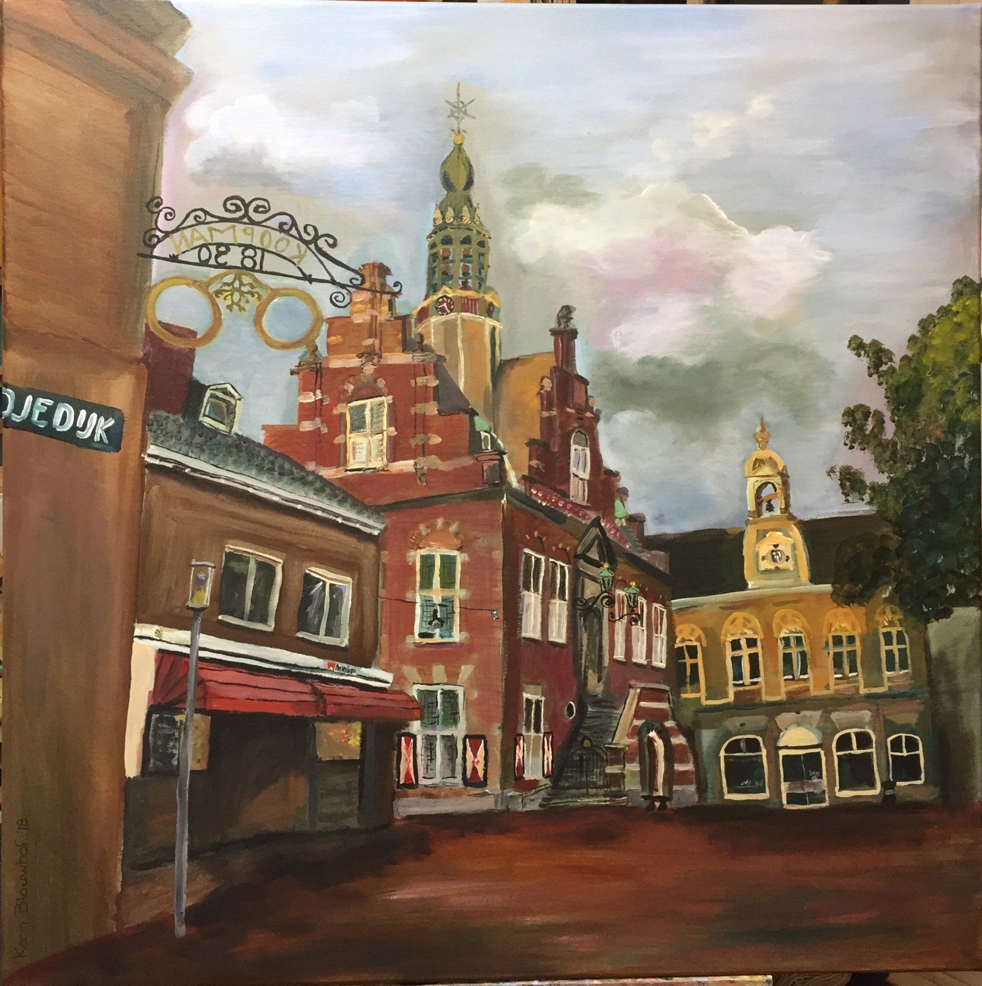 Historische bakstenen straat met een kerktoren, oude winkelpanden en een bewolkte hemel.