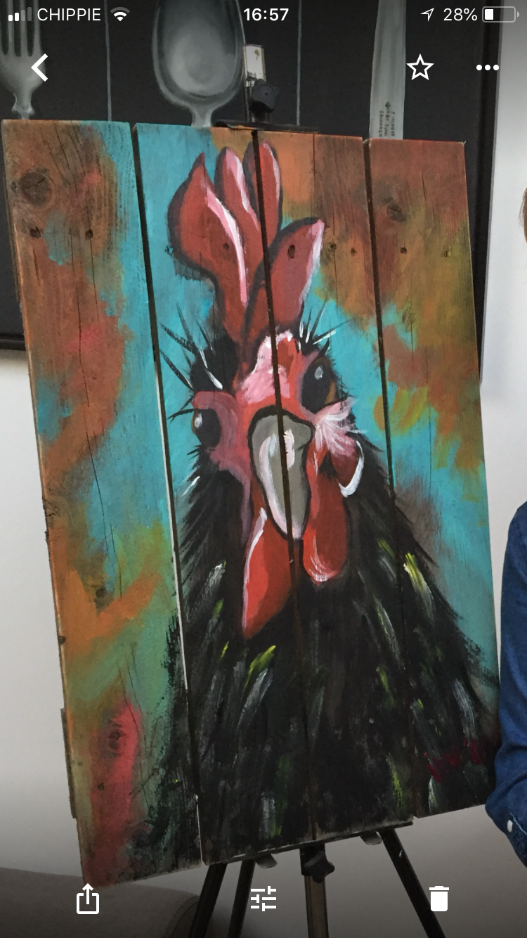 Een groep mensen poseert binnen met kleurrijke schilderijen, lachend en kunstwerken vasthoudend in een gezellige lounge.